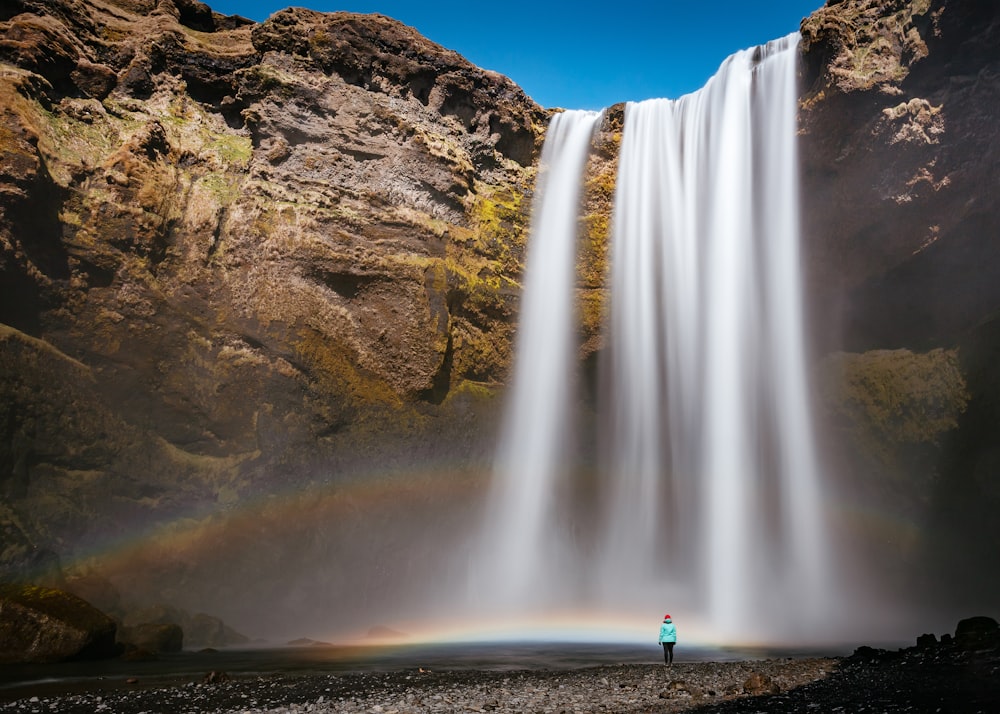 person walking beside waterfall