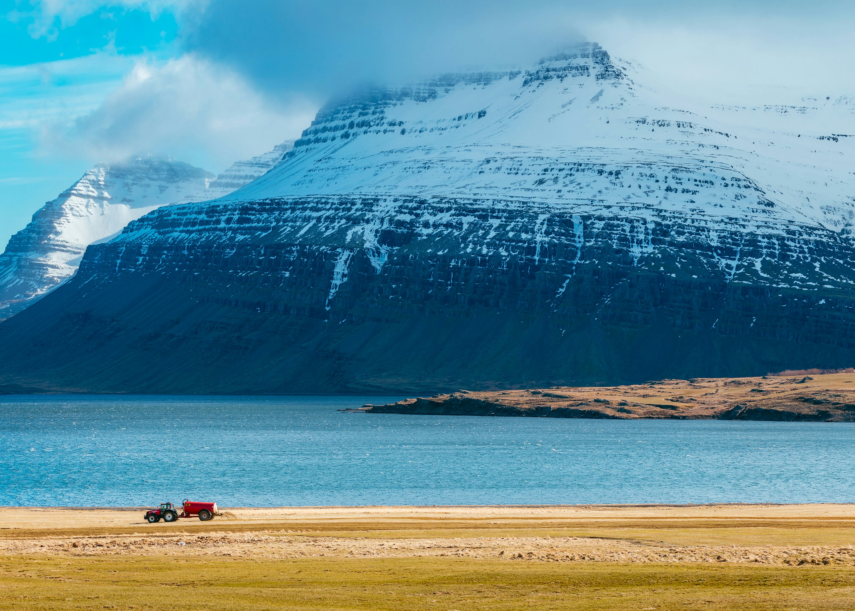 snow capped mountain next to body of water