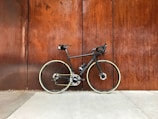 black road bike parked beside brown wooden wall