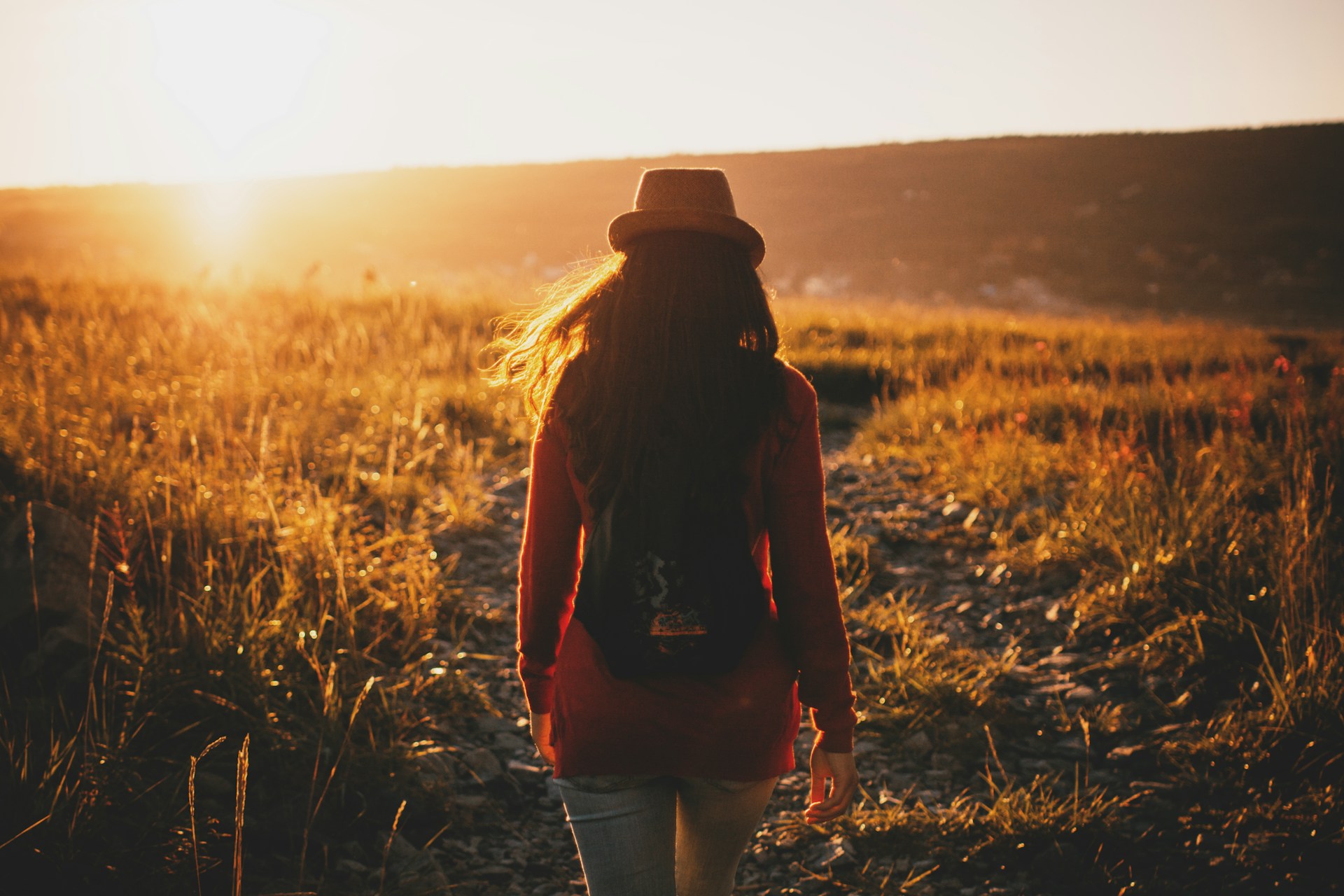 woman walking on grass plains during sunset