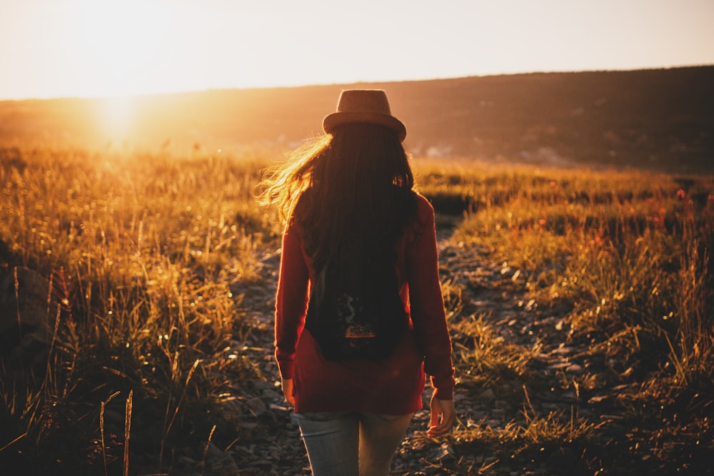 femme marchant sur les plaines d’herbe au coucher du soleil