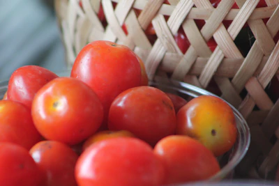 Close-up of a fresh basket of local farm produce with deep reds and greens, textures vivid in natural light.