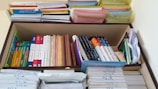 A neatly organized bookshelf containing a variety of textbooks and notebooks. The shelves are filled with academic books such as chemistry, mathematics, and physics, stacked both vertically and horizontally. There are also numerous colorful files and folders neatly arranged on the top shelf. Each section appears meticulously organized, indicating a well-maintained study space.