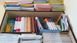 A neatly organized bookshelf containing a variety of textbooks and notebooks. The shelves are filled with academic books such as chemistry, mathematics, and physics, stacked both vertically and horizontally. There are also numerous colorful files and folders neatly arranged on the top shelf. Each section appears meticulously organized, indicating a well-maintained study space.