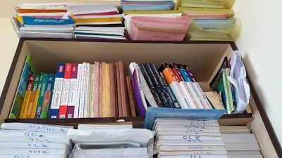 A neatly organized bookshelf containing a variety of textbooks and notebooks. The shelves are filled with academic books such as chemistry, mathematics, and physics, stacked both vertically and horizontally. There are also numerous colorful files and folders neatly arranged on the top shelf. Each section appears meticulously organized, indicating a well-maintained study space.
