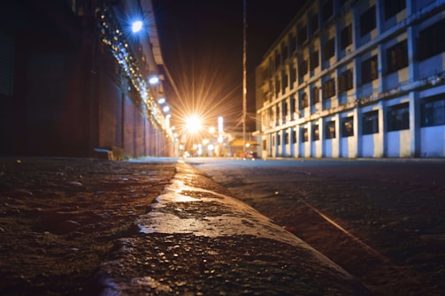 Nighttime shot of a gritty city street freshly paved, glowing under the orange streetlights.