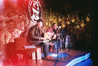 Penelope Torribio and Otis Roy performing together on stage with guitars under warm lighting.