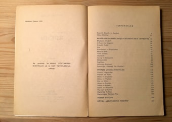 The image shows an open book on a light wood surface. The left page contains some text in Turkish, mentioning the fourth edition from 1982, and a note about the publication. The right page features a table of contents titled 'İ&Ccedil;İNDEKİLER', listing topics related to Bertrand Russell, philosophical and modern issues, with corresponding page numbers.
