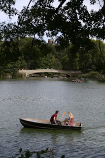 A couple enjoying a peaceful boat ride on a calm lake surrounded by lush greenery.