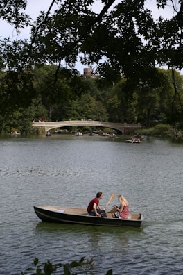 Couple taking a scenic boat ride on a tranquil lake.