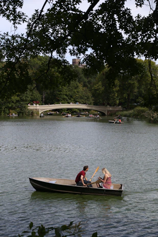 A couple enjoying a peaceful boat ride on a calm lake surrounded by lush greenery.