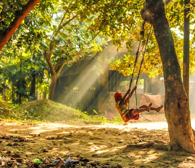 A joyful child swinging high with bright sunshine behind.