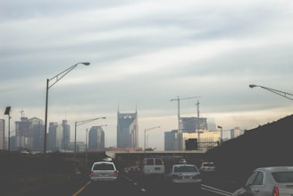 A modern cargo truck driving on a highway with city skyline in the background.