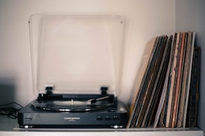Collection of classic vinyl records fanned out on a wooden table with a turntable in the background