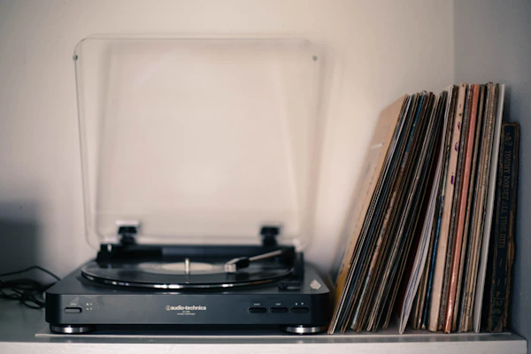 A collection of retro vinyl records stacked beside a vintage record player.