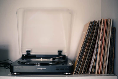 Close-up of vintage vinyl records stacked beside a modern digital player.