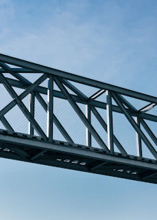 Completed metal bridge structure spanning a river with clear blue sky