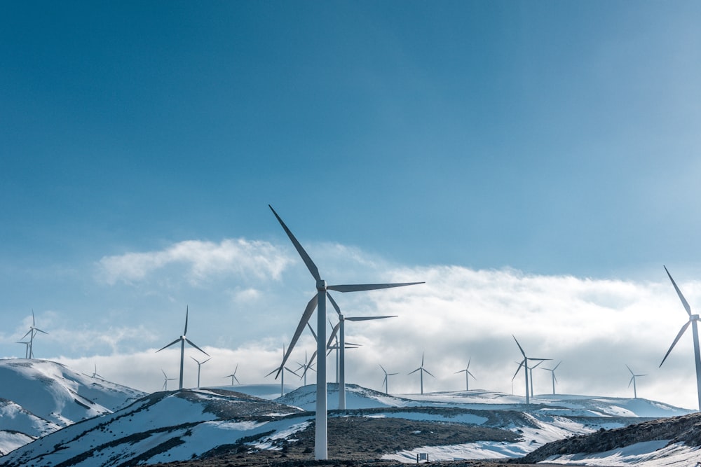 Windkraftanlagen auf verschneiten Bergen unter strahlend blauem Himmel während des Tages