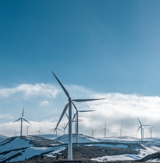 wind turbines on snowy mountain under clear blue sky during daytime