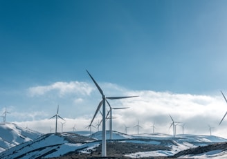 wind turbines on snowy mountain under clear blue sky during daytime