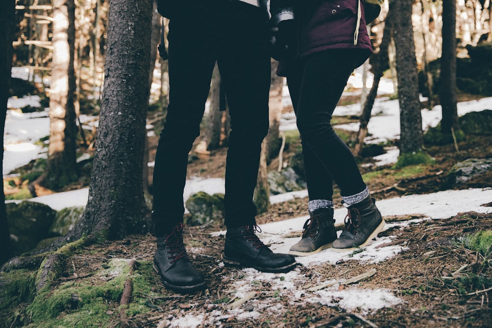 two person wearing black pants and black shoes standing near trees at daytime