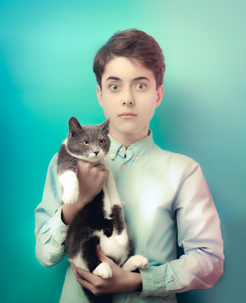 woman in white long sleeve shirt holding black and white cat