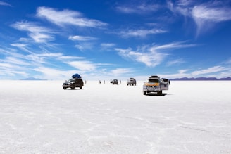 sports utility vehicles on desert under cloudy blue sky during daytime