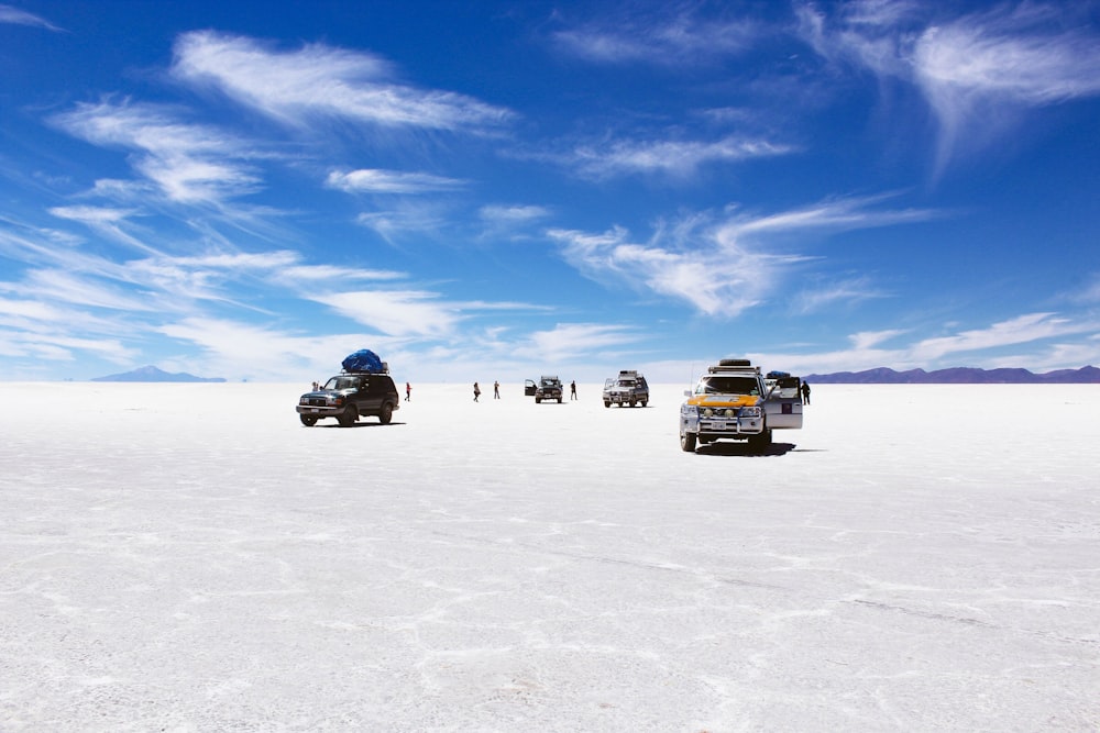 sports utility vehicles on desert under cloudy blue sky during daytime