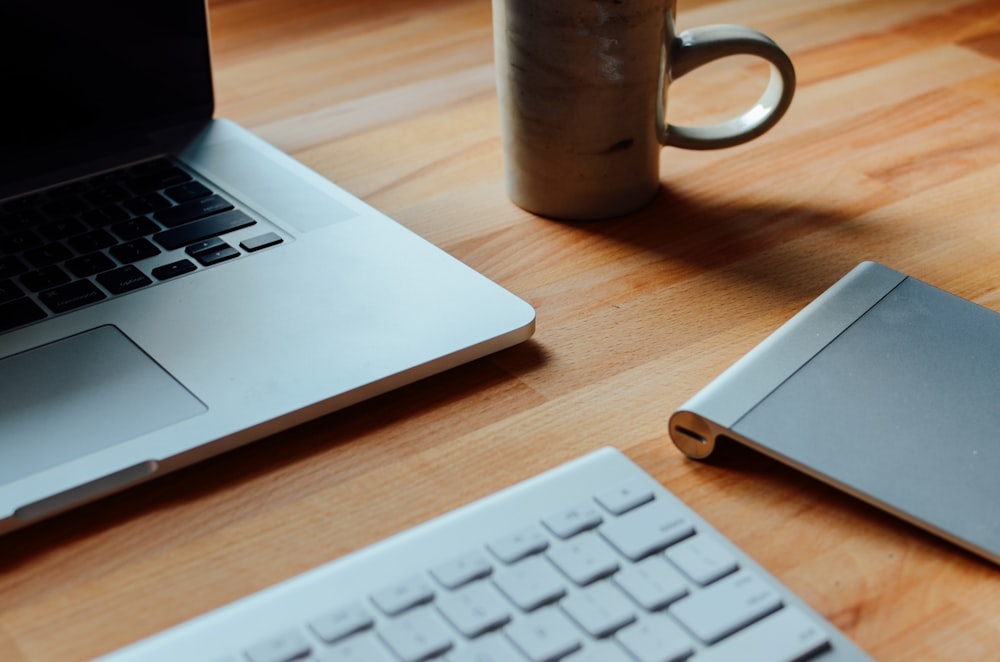 MacBook Pro beside brown ceramic mug