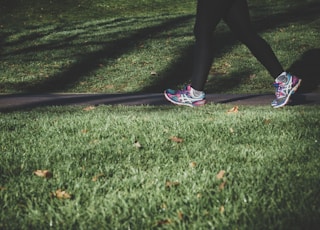 shallow focus photography of person walking on road between grass