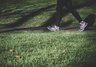 shallow focus photography of person walking on road between grass