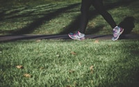 shallow focus photography of person walking on road between grass