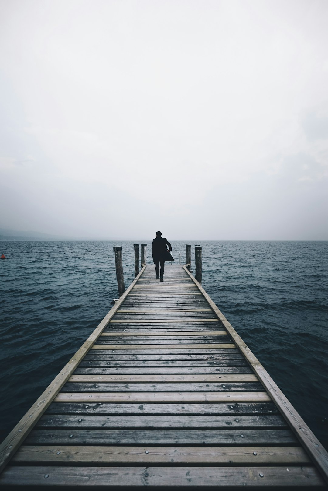 man walking on dock surrounded by ocean during daytime