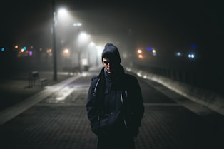 homem andando sozinho no nevoeiro à noite perto das luzes da rua