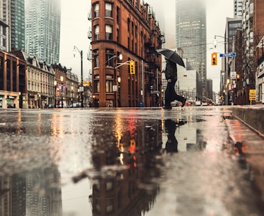 man using umbrella crossing the street during daytime