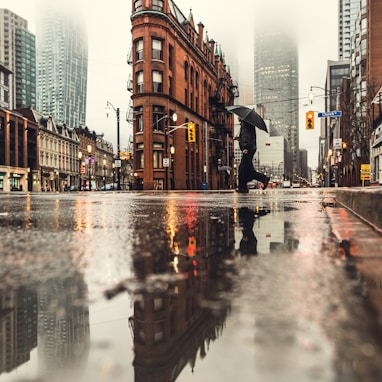 man using umbrella crossing the street during daytime