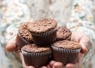 shallow focus photography of person holding 5 cupcakes