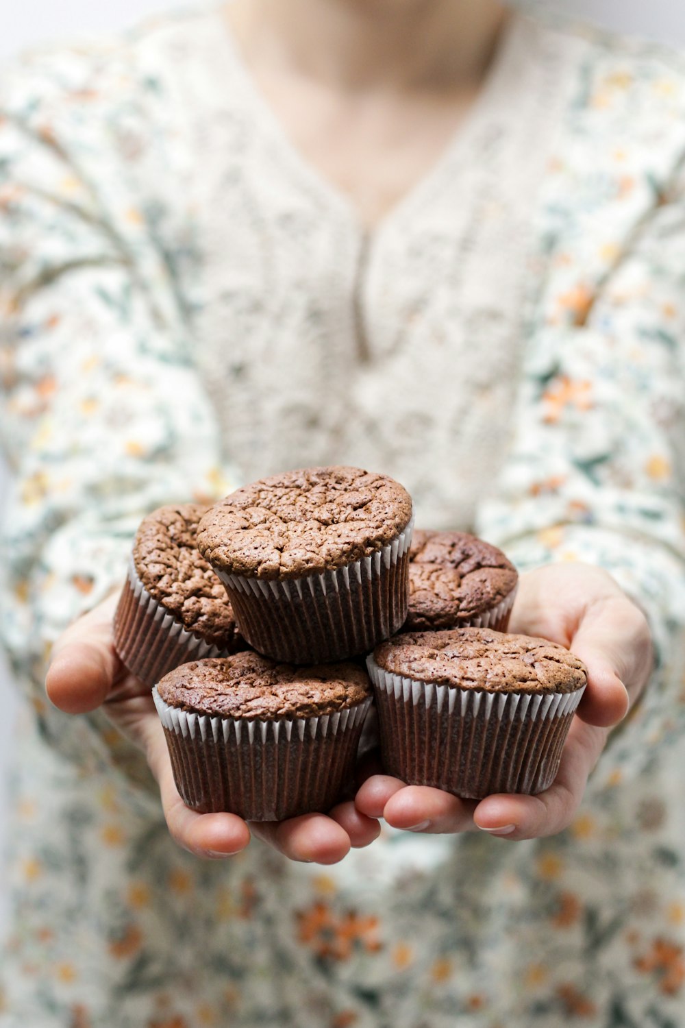 Photographie à mise au point peu profonde d’une personne tenant 5 cupcakes