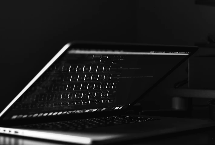 A focused software developer writing code on a laptop with golden light reflecting off the screen.