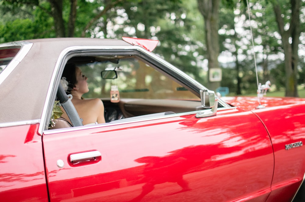 woman riding on red coupe