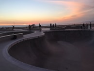 Wide shot of a skatepark at sunset with vibrant colors reflecting on the concrete.