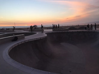 Wide shot of a skatepark at sunset with vibrant colors reflecting on the concrete.