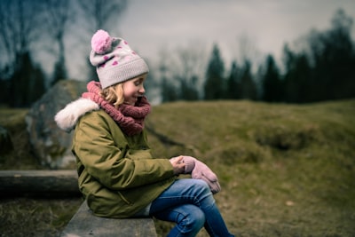 smiling girl sitting on brown bench mittens zoom background