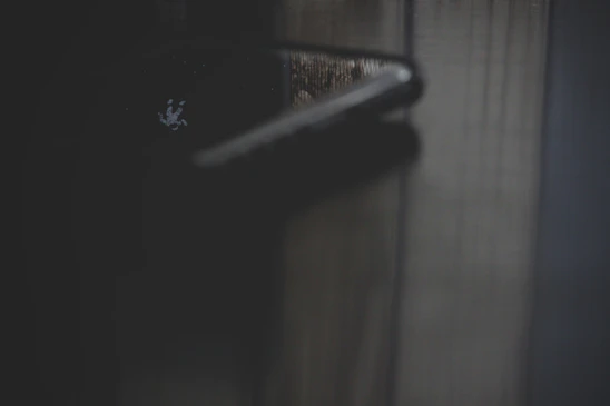 Close-up of a luxury metallic door lock reflecting warm cinematic light in a dark, elegant setting.