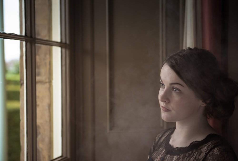 woman standing near window looking outside