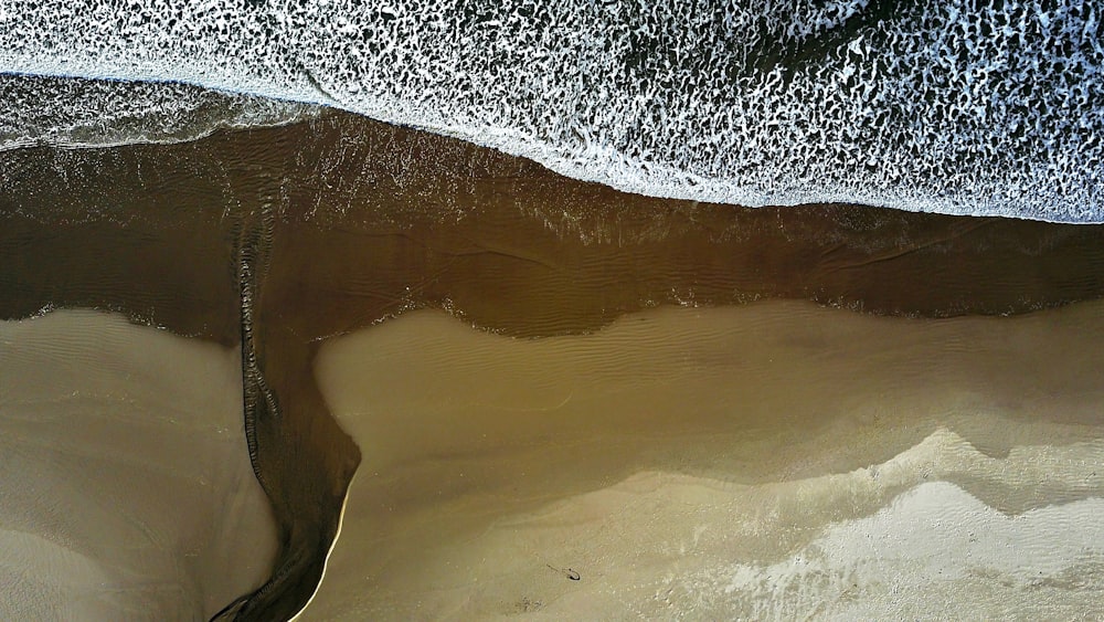 Vista de dron del océano bañado en la costa de la playa de arena en Arch Cape, Oregón, Estados Unidos
