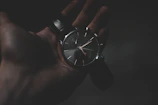 Minimalist display of carbon fiber and fluororubber straps against a dark textured background.