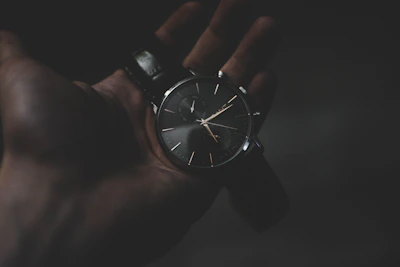 Minimalist display of carbon fiber and fluororubber straps against a dark textured background.