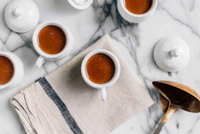 white ceramic teacup filled with red liquid napkin teams background