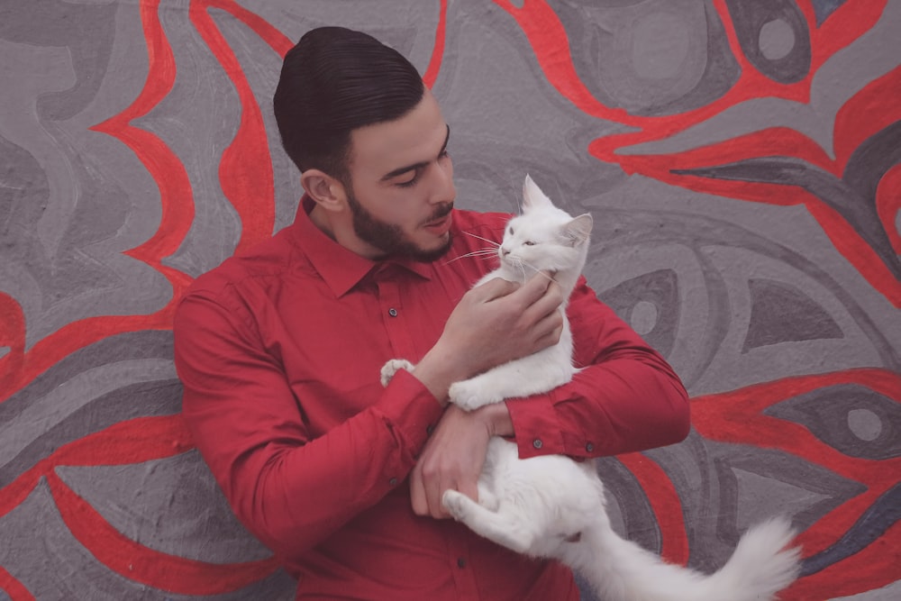 man in red dress shirt holding white cat